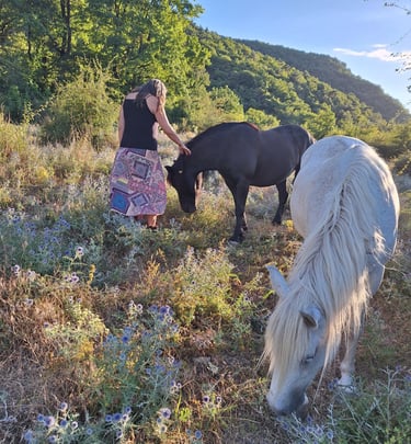 A woman standing in a mountain landscape in the south of france with peacefully grazing horses