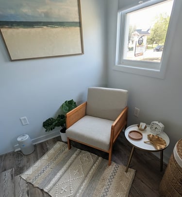 a waiting area with a chair and a table with a painting on the wall