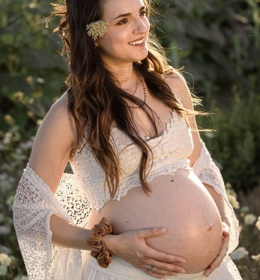 a pregnant woman in a white dress and sunflowers
