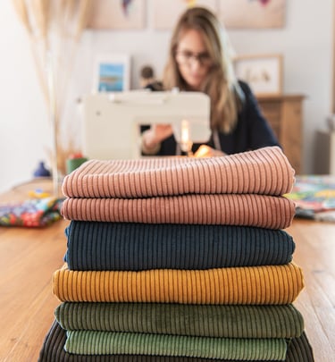 séance photo professionnelle d'une couturière en train de coudre avec ses tissus devant