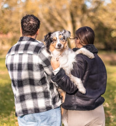 séance couple avec leur chien, un berger australien, qu'ils tiennent dans leur bras