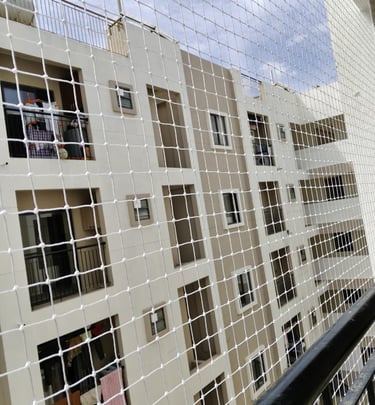 Close-up of a freshly installed white balcony safety net against a sunny sky background