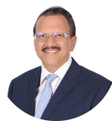 Professional portrait of a smiling Indian male executive in a blue suit and glasses against a white background.