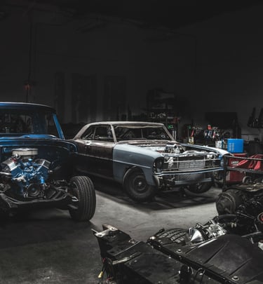 Classic vintage cars undergoing engine restoration in a professional automotive repair shop.
