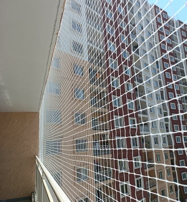 Technician from Arjilli Enterprises carefully fitting a safety net on a residential balcony.