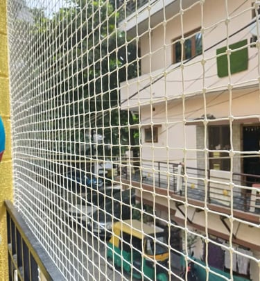 A family enjoying their balcony safely protected by a neatly installed safety net by Arjilli Enterpr