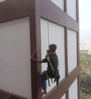 Technician carefully installing a balcony safety net on a residential building