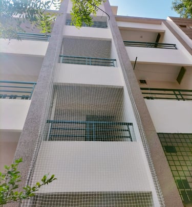 Technician carefully fixing a pigeon net frame on a high-rise apartment duct