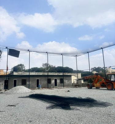 Evening view of a cricket ground illuminated by floodlights, showcasing the installed boundary nets