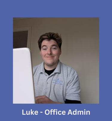 Portrait of Luke, office administrator, smiling and sat in front of a laptop.