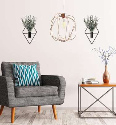 Modern living room with a grey armchair, geometric wall planters, and a copper cage pendant light.