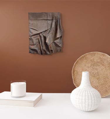 Kunstværk i brunt draperet stof på væg