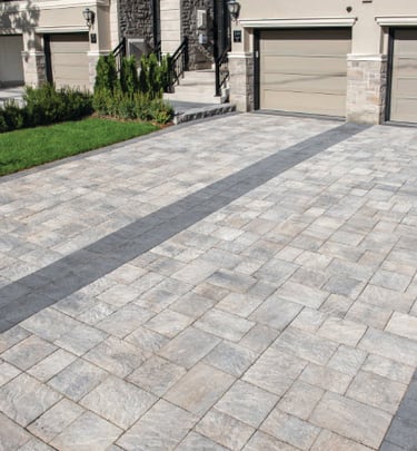 a brick paver driveway with earthy colors and dark center and border