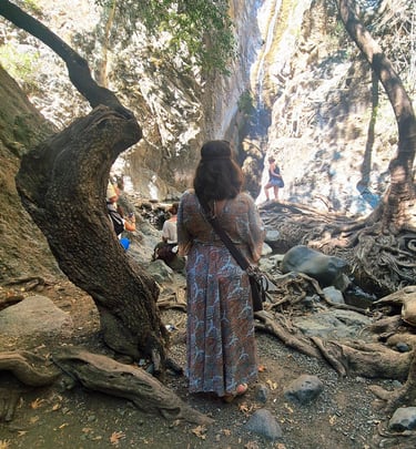 a woman in a dress looking at a Platres waterfall during a Cyprus nature photography tour