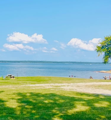 a park bench with benches and people sitting on the grass by the lake
