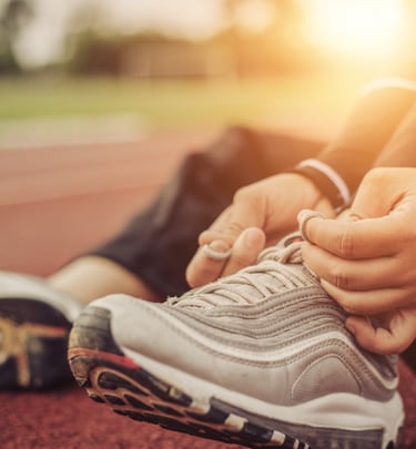 a person tieing their shoes at sunset on a track.