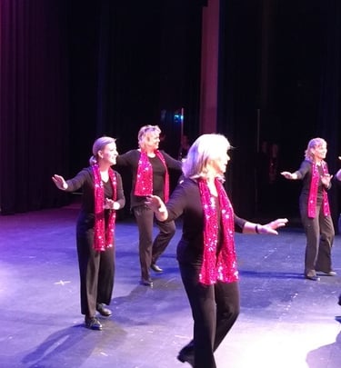 a group of women tap dancers in pink and black outfits on stage