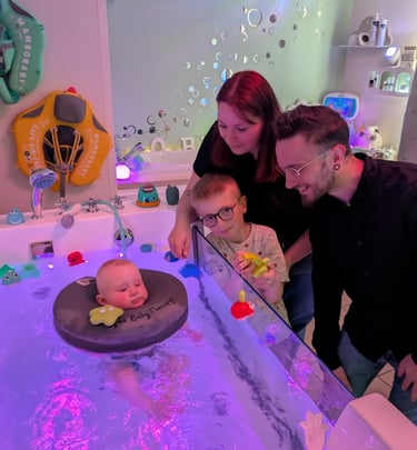 famille heureuse regardant leur bébé dans le bain d'hydrothérapie