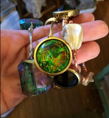 a person holding a necklace with a green glass pendant