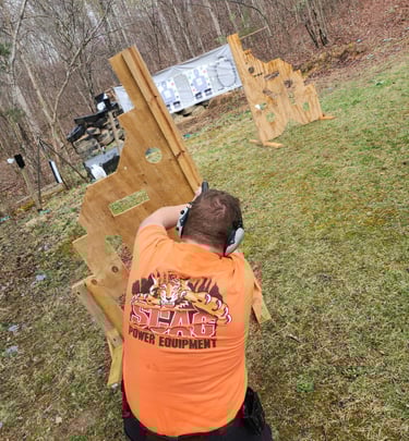 Kneeling man engaging targets from a barrier using self-defense firearm during training.