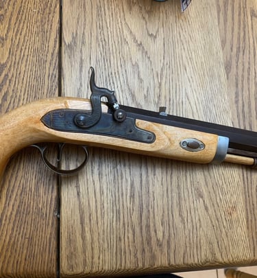 Custom Built muzzleloader pistol with a light wood stock on a rustic oak table.