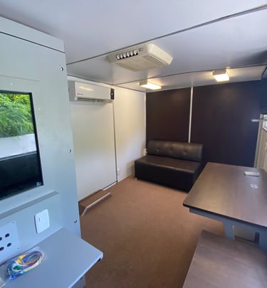 Interior de unidad médica móvil equipada con cabina audiométrica y mobiliario para atención médica.