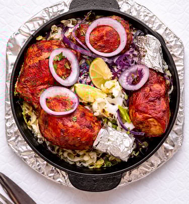 Creamy Indian butter chicken curry in a copper bowl garnished with cashews, almonds, and cream drizzle.