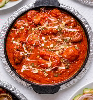 Spicy Indian butter chicken or shrimp tikka masala in a cast iron skillet with cream and nuts.