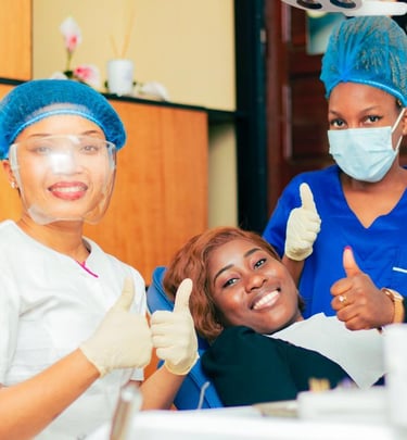 Smiling dental patient and dentists giving thumbs up during a successful checkup.