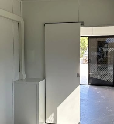 Interior of a modern white modular cabin featuring a sliding door and a security mesh screen door.