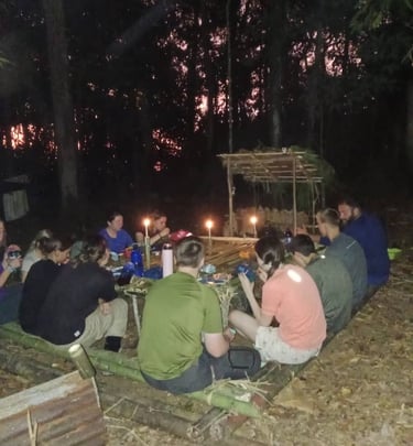 a corporate group jungle survival camp enjoying dinner with candle