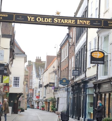 image of a ols street in York. has a sign across the road that has aname of a inn.