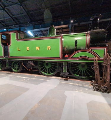 an old steam engine with LSWR painted on the side. Static  within an exhibtion at the NRM, York
