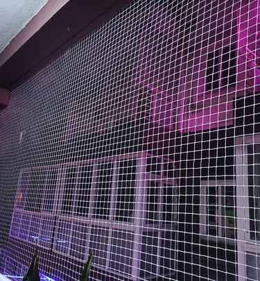 Close-up of a sturdy pigeon net tightly fitted on a balcony railing with sunlight casting shadows