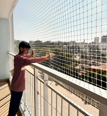 A happy family enjoying their balcony secured with Arjilli safety nets, with lush greenery in the ba