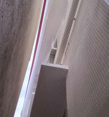 Technician carefully fitting a safety net around a narrow duct space.