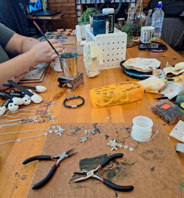Jewelry making workspace with pliers, silver chains, and beads on a wooden table for DIY crafts.