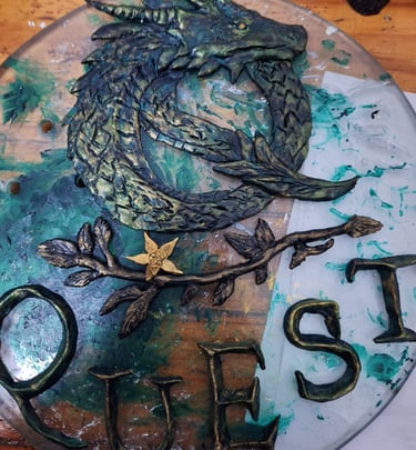Hand-painted dragon sculpture and Quest sign art with metallic green and gold details on a glass base.