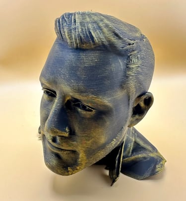 A 3D printed bust of a man with a metallic bronze and black finish on a tan background.