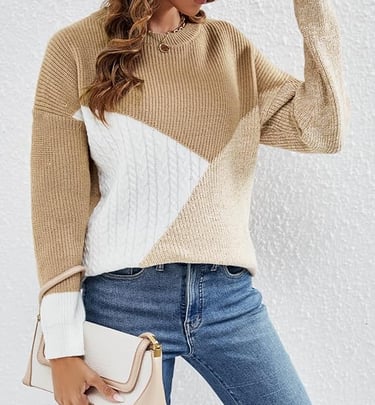 Woman wearing a tan and white colorblock cable knit sweater with blue denim jeans.