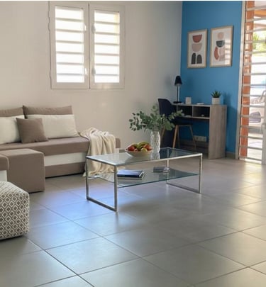 Salon lumineux avec canapé, espace bureau et décoration moderne, loc saisonnière à Ducos Martinique