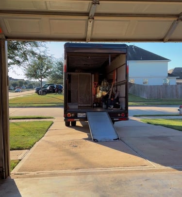 Professional moving truck with ramp parked in a driveway, loaded with furniture for residential relocation.