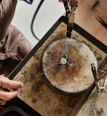 Joyero que utiliza un soplete de gas para soldar un anillo de plata en un bloque de soldadura.