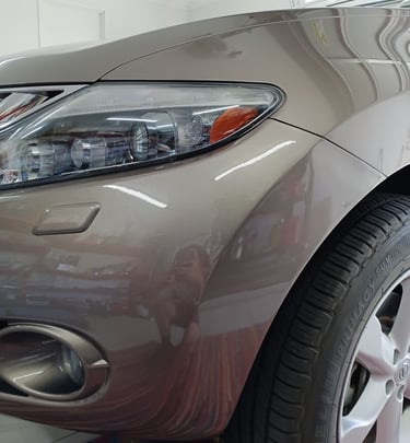 Close-up of a bronze Nissan headlight and fender after Lev Auto Refinishing.