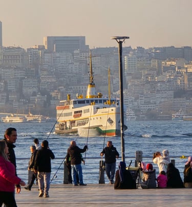 People fishing on a pier with a large ferry boat sailing across the Bosphorus in Istanbul.