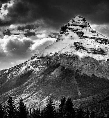 Charity Mountain in the Canadian Rocky Mountains, showcasing it's rugged snow covering and a dramtic sky