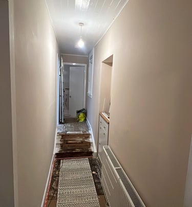 a hallway with freshly painted walls, a carpeted floor and a rug 