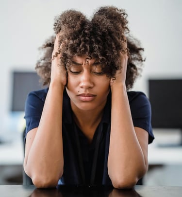 woman with curly hair and blue shirt.  looks tired and anxious