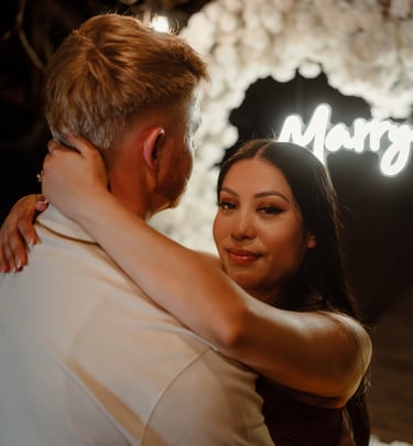 a man and woman standing in front of a neon sign