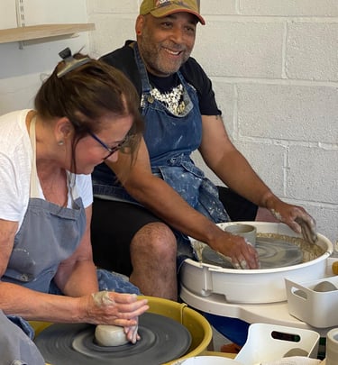 two people enjoying a pottery lesson on the potters wheel